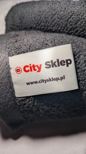 Detal czarnego bawełnianego ręcznika City Sklep: pętelkowa faktura i biała metka z logo